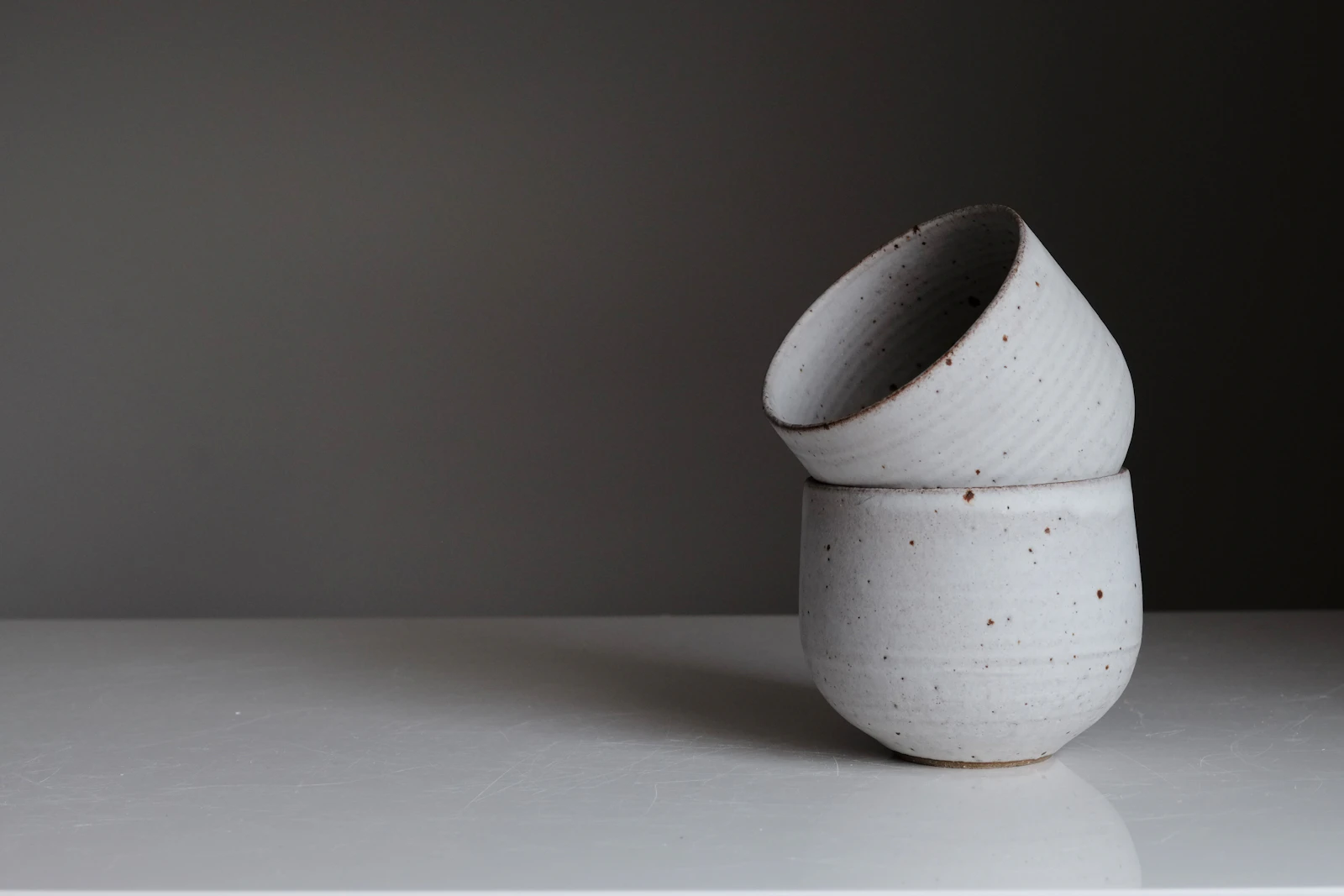 Two speckled ceramic bowls resting together on a neutral surface