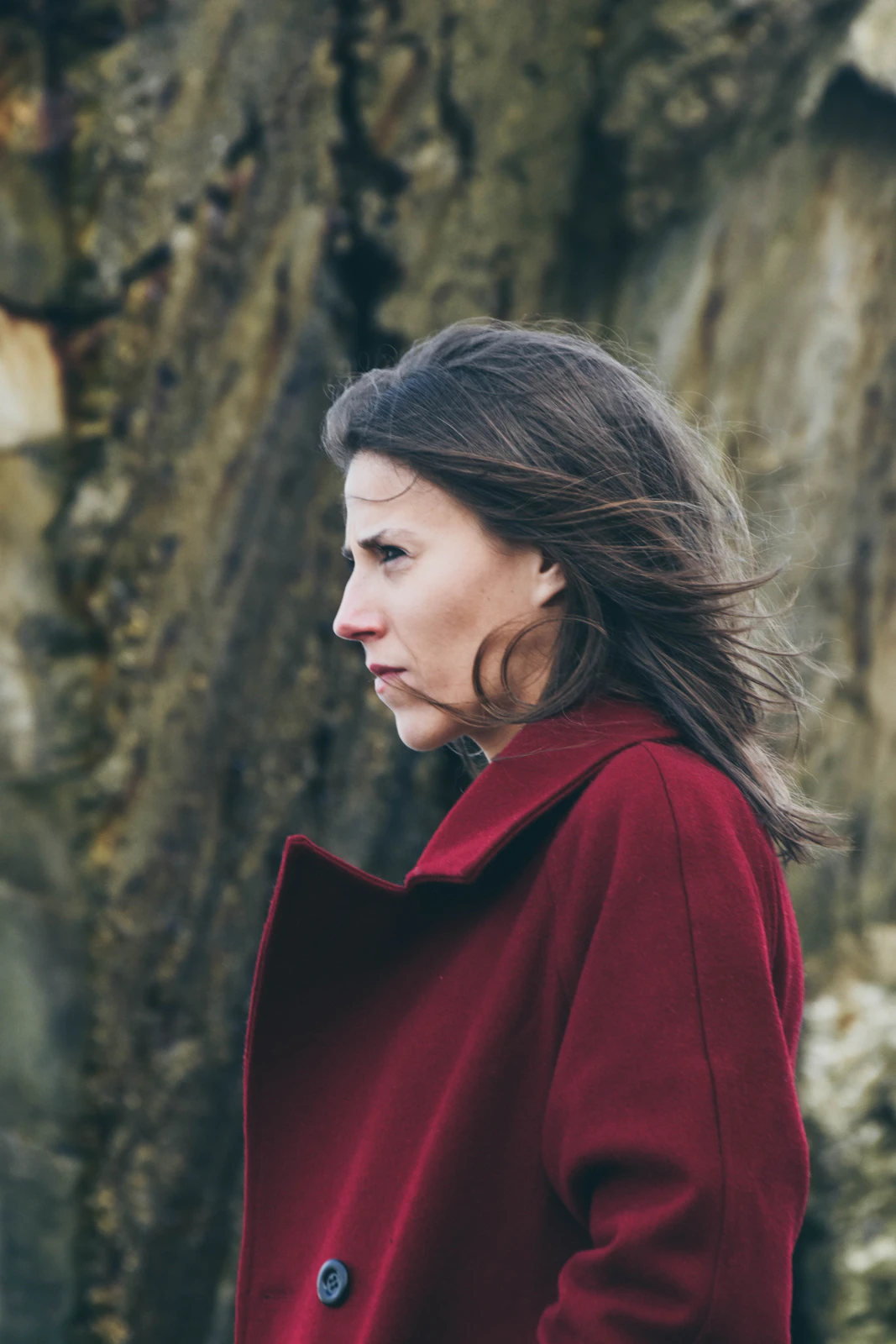 Portrait of a woman wearing a burgundy coat in a wooded setting